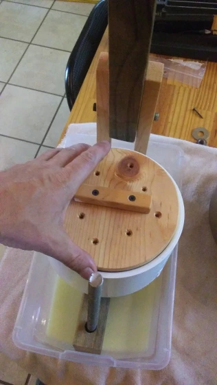 putting top plate plunger on top of cheese in press